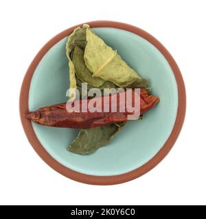 Vista dall'alto delle foglie di lime di kaffir e di un peperoncino rosso in una piccola ciotola isolata su sfondo bianco. Foto Stock