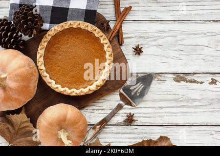 Torta intera di zucca appena sfornata con ingredienti su uno sfondo di tavolo di legno bianco. Vista dall'alto con spazio di copia. Foto Stock