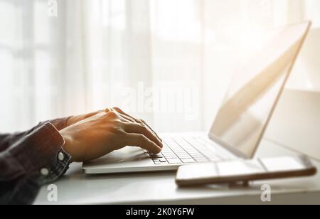 Primo piano delle mani di un uomo che utilizza un computer portatile in ufficio a casa. Concetto di ricerca sul Web, navigazione delle informazioni. Messa a fuoco morbida Foto Stock