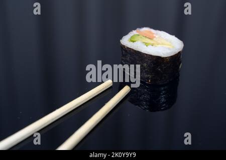 un sushi con bacchette su sfondo scuro Foto Stock