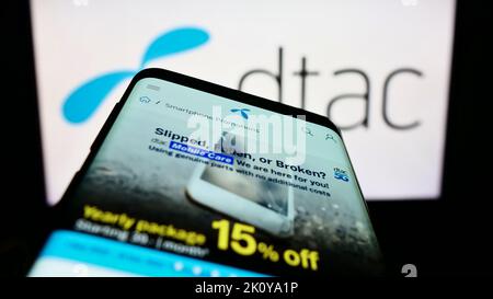 Smartphone con pagina Web di Total Access Communication Public Company Limited (DTAC) sullo schermo davanti al logo. Messa a fuoco in alto a sinistra del display del telefono. Foto Stock