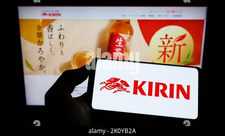 Persona che tiene un telefono cellulare con il logo della Kirin Brewery Company Limited giapponese sullo schermo di fronte alla pagina Web aziendale. Messa a fuoco sul display del telefono. Foto Stock