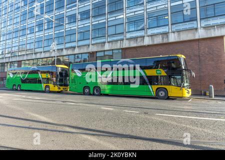 Due autobus verdi e gialli a due piani parcheggiati e un edificio in vetro nella stazione degli autobus di Busaras, Dublino, Irlanda. Foto Stock