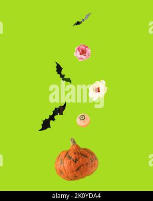Sfondo di Halloween con zucca arancione, pipistrelli neri, bulbo oculare e fiori rosa e bianchi che cadono su sfondo verde. Foto Stock