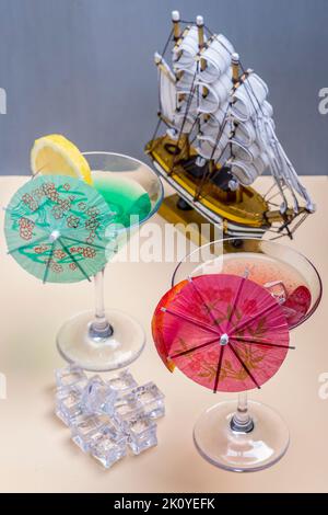 Due bicchieri con cocktail colorati e una nave modello sullo sfondo Foto Stock