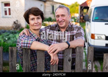 coppia anziana vicino alla recinzione che abbraccia il villaggio Foto Stock