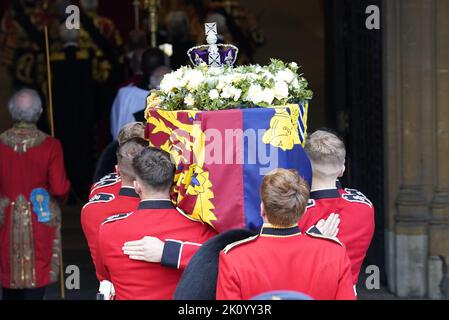 Il partito portatore trasporta la bara, drappeggiato nello Standard reale con la corona di Stato imperiale posta in cima, della regina Elisabetta II, nella sala di Westminster, Londra, dove si trova in stato davanti al suo funerale il lunedì. Data immagine: Mercoledì 14 settembre 2022. Foto Stock