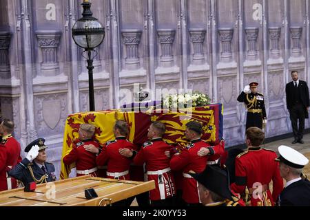 Il partito portatore trasporta la bara, drappeggiato nello Standard reale con la corona di Stato imperiale posta in cima, della regina Elisabetta II, nella sala di Westminster, Londra, dove si trova in stato davanti al suo funerale il lunedì. Data immagine: Mercoledì 14 settembre 2022. Foto Stock