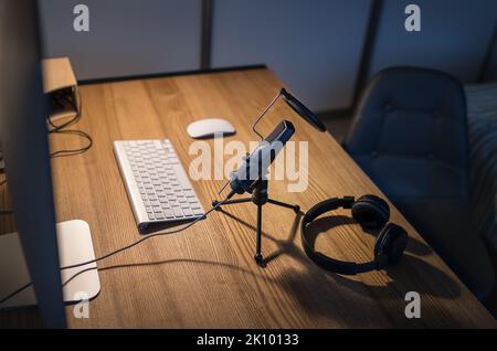 Piccolo studio di streaming audio: Microfono con filtro pop, cuffie, computer desktop, tastiera e mouse. Registrazione audio da studio di home sound moderno o Foto Stock