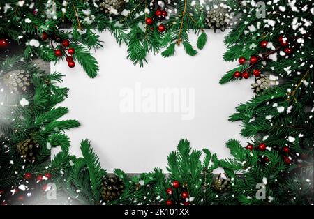 Cornice natalizia in rami di abete scuro, coni, bacche rosse e decorazioni. Composizione natalizia con cornice di rami di abete e coni di pino. M Foto Stock
