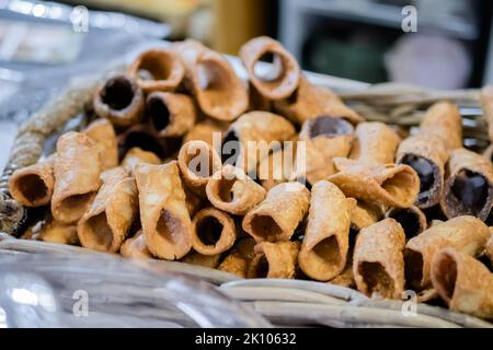 Dolci cannoli fritti vuoti nel cestino al banco del mercato alimentare Foto Stock