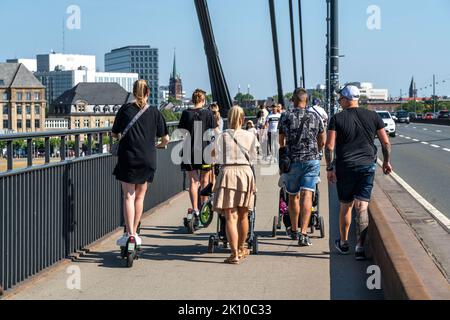 Pedoni e scooter elettronici su un marciapiede, avvicinandosi e in modo reciproco, guida illegale sul marciapiede da parte di utenti di scooter elettronici, Düsseldorf, NRW, Foto Stock