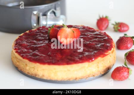 Torta al formaggio di fragola. Torta al formaggio morbida e cremosa con guarnizioni di fragole fresche fatte in casa. Sparare con il piatto da forno sullo sfondo e fresco Foto Stock