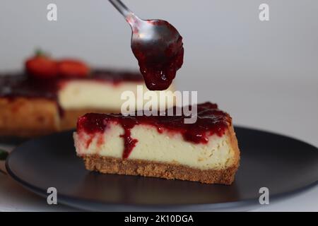 Fetta di torta al formaggio Strawberry. Torta al formaggio cremosa e liscia con salsa di fragole fresca fatta in casa. Sparare con fragole fresche intorno Foto Stock