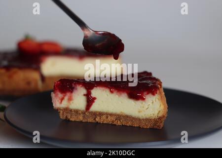 Fetta di torta al formaggio Strawberry. Torta al formaggio cremosa e liscia con salsa di fragole fresca fatta in casa. Sparare con fragole fresche intorno Foto Stock