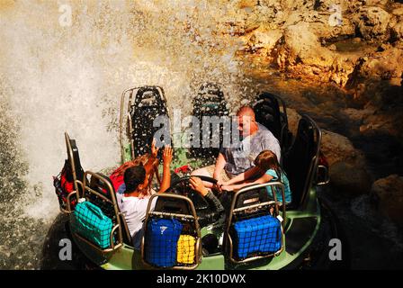 Una famiglia si bagna e si bagna mentre cavalca sul Grizzly River Run, un giro in acqua nel parco divertimenti California Adventure di Disneyland Foto Stock