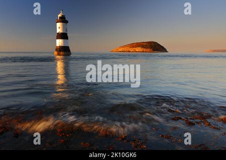 Penmon Lighthouse e Puffin Island in una tranquilla serata estiva. Anglesey, Galles del Nord, Regno Unito. Foto Stock