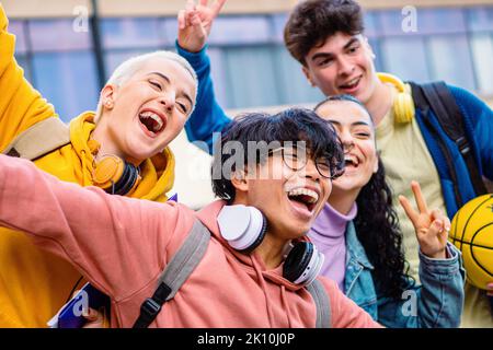 Gruppo di giovani amici multietnici che si divertono e sorridono. Quattro diversi studenti adolescenti che si godono l'estate. Concetto di istruzione. Foto Stock