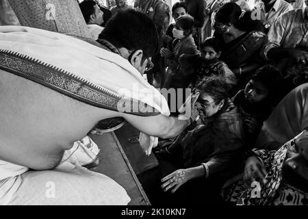 Howrah, Bengala Occidentale, India - 14th Ottobre 2021 : Turohit indù che mette il santo tilak sulla fronte dei devoti durante i pushpanjali puja alla dea Durga. Foto Stock