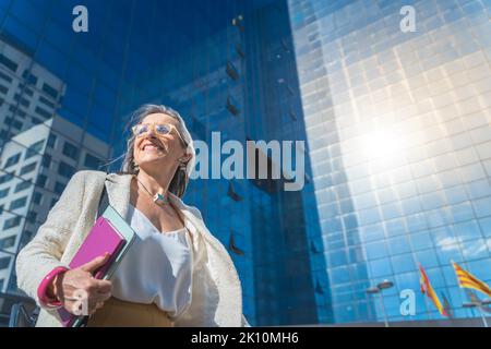Donna d'affari sicura, concentrata e potente che cammina in un moderno edificio di uffici. Giovane professionista aziendale che va o lascia il posto di lavoro Foto Stock