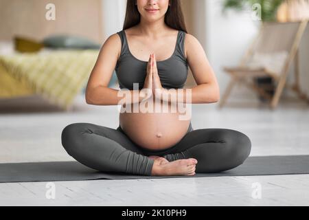 Gravidanza Yoga. Crosed Shot di giovane donna incinta seduta in posizione di loto Foto Stock