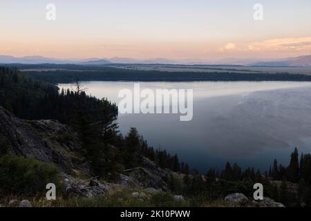 Il lago Jenny riposa sotto un cielo serale e la valle di Jackson Hole. Grand Teton National Park, Wyoming Foto Stock