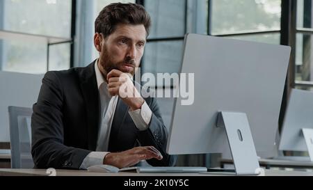Messo a fuoco caucasico bearded adulto 40s uomo CEO azienda worker manager boss businessman lavorando al computer in ufficio alla ricerca di soluzione del problema decidere Foto Stock
