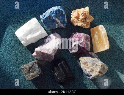 Gemme multicolore, minerali su una piastra di ceramica blu. Quarzo rosa, turchese, labradorite, sodalite, fluorite, gesso rosso, tormalina nera, scho Foto Stock