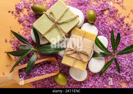 Composizione con saponi d'oliva, sale marino e pietre termali su sfondo colorato, primo piano Foto Stock