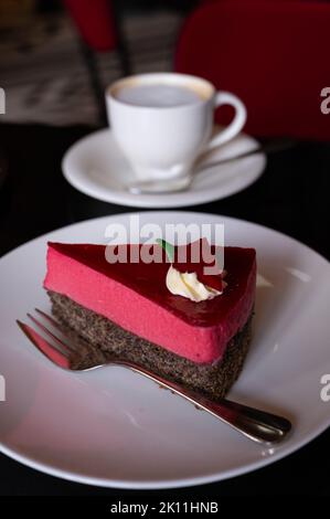 Pezzo di famosa torta di semi di papavero con mousse di lamponi di origine austriaca servito con panna montata e tazza di caffè in vecchio classico caffè-ristorante in Foto Stock