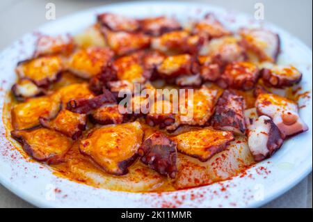 Gustosi frutti di mare, polpo alla griglia in stile galiziano con paprika pimento rosso e patate serviti nel ristorante spagnolo Foto Stock