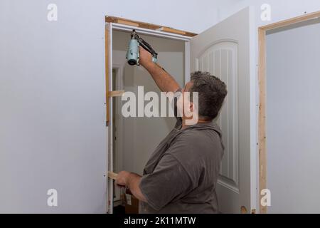 Un falegname di rivestimento installa le porte interne in una casa di nuova costruzione come parte del processo di costruzione Foto Stock