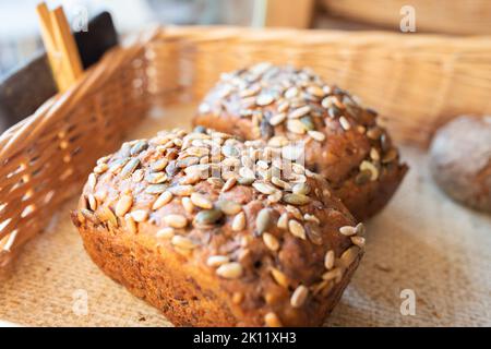 Pane artigianale pronto con semi sul banco in una piccola panetteria. Vista frontale. Foto Stock