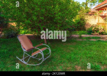 Sedia a dondolo nel giardino di una casa di campagna Foto Stock