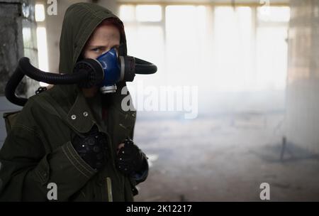 Giovane donna sopravvissuta pandemica in maschera a gas che guarda di fronte a lei sullo sfondo con area di guerra apocalittica intorno. Donna triste nel respirare ossi ma Foto Stock