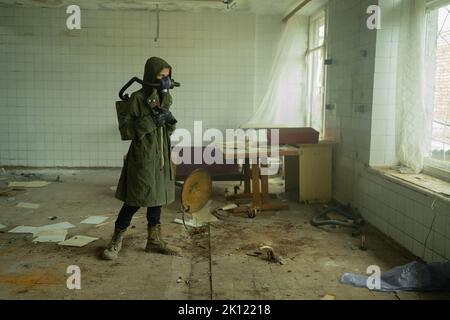 Inquinamento atmosferico post-apocalittico. Survivor in tatters e maschera a gas sullo sfondo abbandonato costruzione. Concetto di protezione della natura e di inquinamento dell'aria Foto Stock