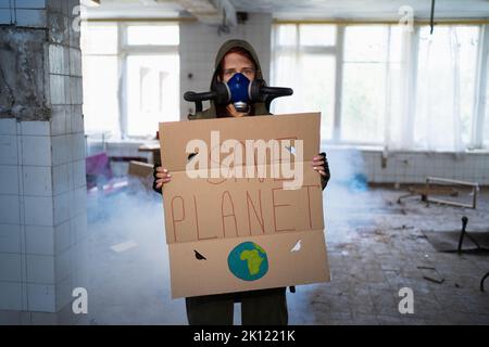 Donna post apocalittico sopravvissuto con maschera a gas circondata da fumo con banner salvare pianeta. Concetto di catastrofe globale. Pandemia, inquinamento atmosferico, verde Foto Stock