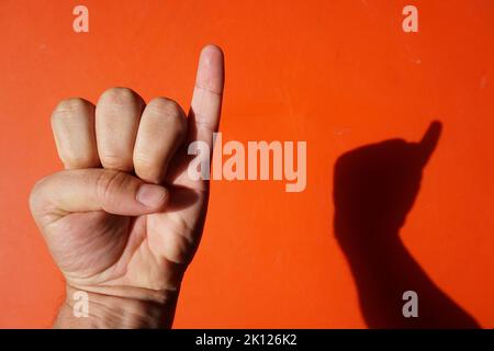 mano segno ed ombra con appena il dito piccolo sollevato Foto Stock