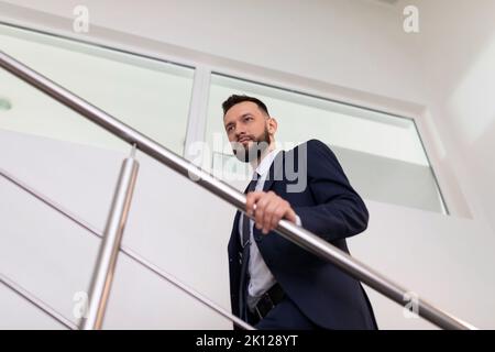 un uomo d'affari in un costume sale le scale fino in cima. Concetto di crescita professionale. Foto Stock