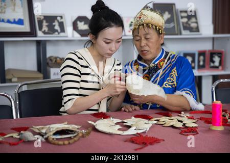 (220915) -- HARBIN, 15 settembre 2022 (Xinhua) -- Shang Meihan (L) impara a fare un artigianato tradizionale di pelle di pesce da un artigiano esperto nel villaggio etnico di Hezhe di Zhuaji nella città di Wusu di Fuyuan, provincia di Heilongjiang nella Cina nord-orientale, 7 settembre 2022. Gli Hezhes sono uno dei più piccoli gruppi etnici minoritari della Cina. Vivono principalmente con la caccia e la pesca nelle pianure della provincia di Heilongjiang, nel nord-est della Cina. Shang Meihan è una giovane donna del gruppo etnico di Heze. Mentre lavora come un funzionario pubblico nella città di Wusu, il 25-year-old è anche un part-time 'ambasciado culturale Foto Stock