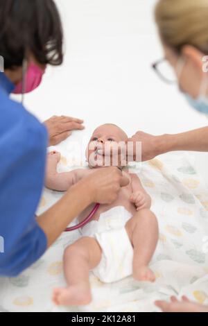 Bambino sdraiato sulla schiena mentre il medico lo esamina durante un controllo medico standard Foto Stock