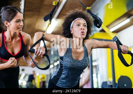 Belle donne in forma, amici che si allenano in palestra insieme. Sport, concetto di persone Foto Stock