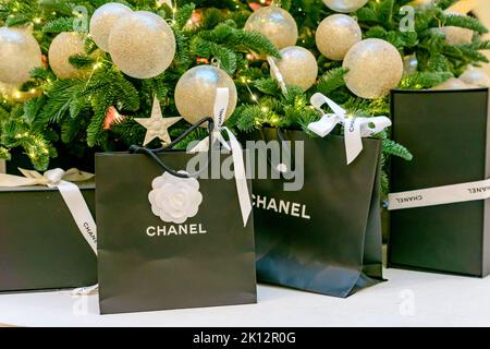 Mosca, Russia - 15 dicembre 2021 - logo Chanel su sacchetti di carta nera con regali sotto l'albero di natale. Lussuoso marchio di abbigliamento, accessori e cos Foto Stock