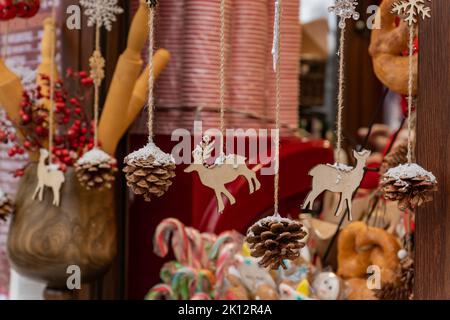 primo piano di ghirlanda di materiali naturali. Statuette in legno e coni di pino su un cordone. Decorazioni di natale in stile ecologico Foto Stock