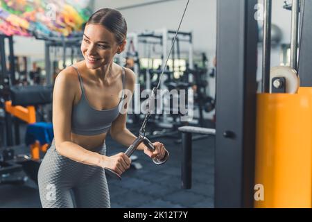 Giovane e bella ragazza caucasica fare esercizio con una macchina a voga, cowboy shot fitness concetto. Foto di alta qualità Foto Stock