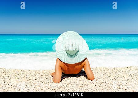 Donna spensierata con cappello di paglia sdraiata su una spiaggia idilliaca, Cefalonia, Isole IONIE, Isole greche, Grecia, Europa Foto Stock