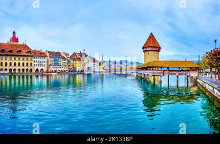 LUCERNA, SVIZZERA - 30 MARZO 2022: Passeggiata lungo la riva del fiume Reuss, godendo di vista sul ponte medievale Kapellbrucke e la torre Wasserturm, su Marc Foto Stock