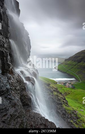 Vista ravvicinata della cascata e del villaggio di Tjornuvik al crepuscolo, l'isola di Streymoy, le isole Faroe, la Danimarca, l'Europa Foto Stock