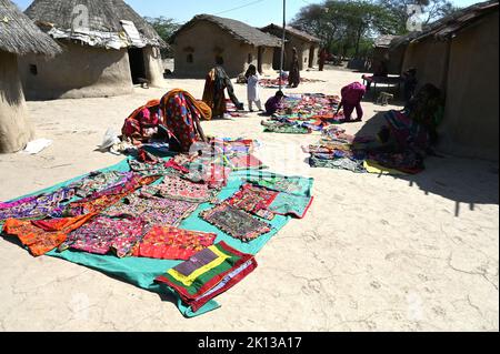 Le donne del villaggio tribale che stendono il loro ricamo tribale fuori delle case murate di fango nel loro villaggio tribale, Kachchh, Gujarat, India, Asia Foto Stock