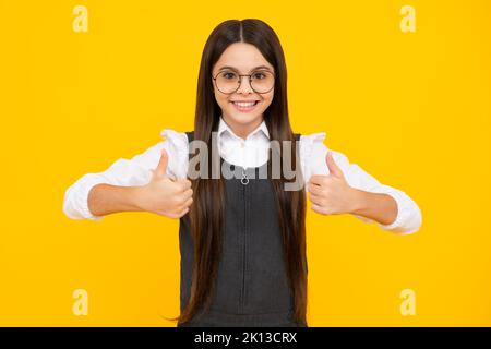 Gesto dei bambini. Piccola studentessa scolastica. Ragazza felice di capretto adolescente in vestiti casuali che mostrano i pollici in su. Faccia felice della ragazza, positiva e sorridente Foto Stock